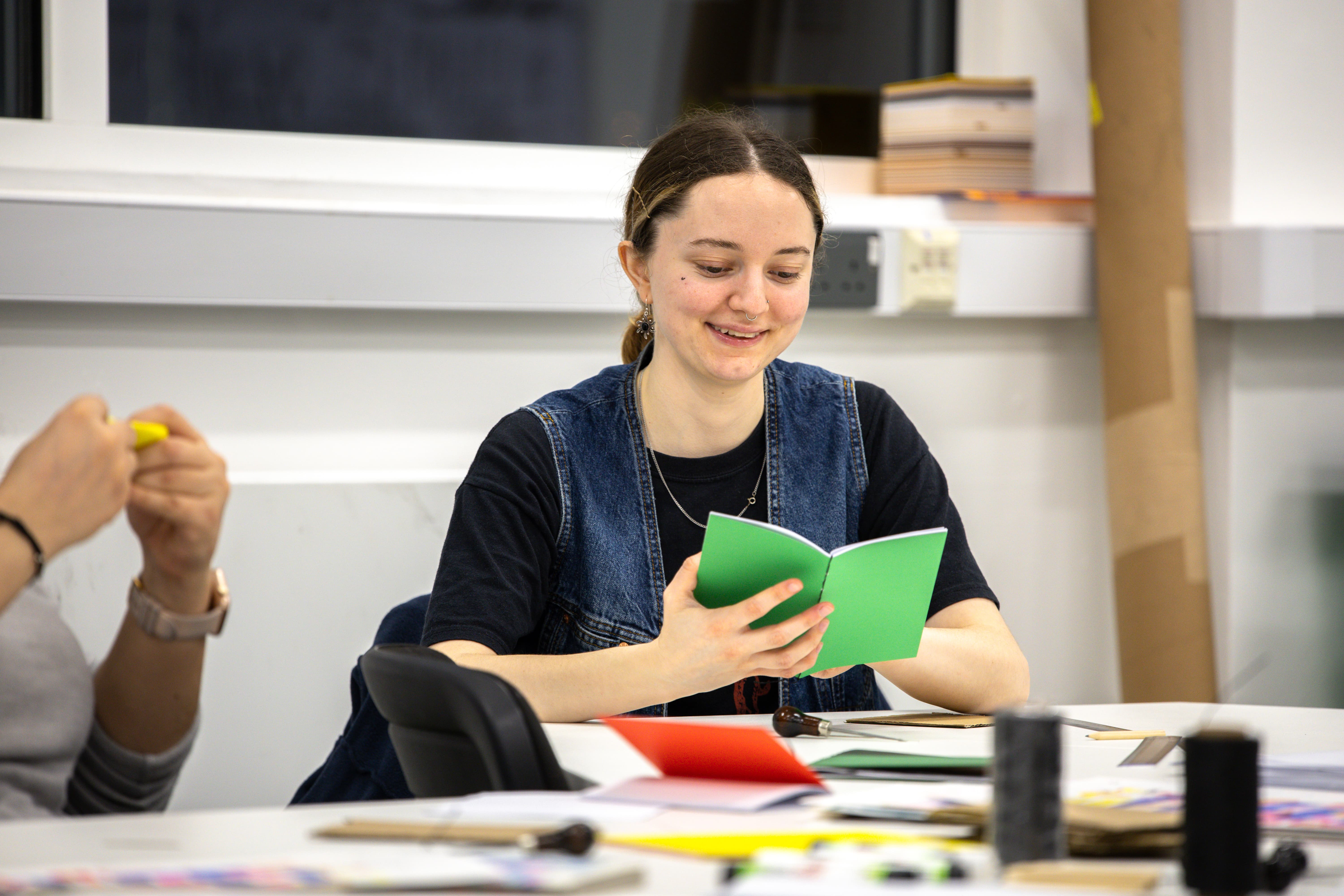 A woman holding a small green book and smiling.